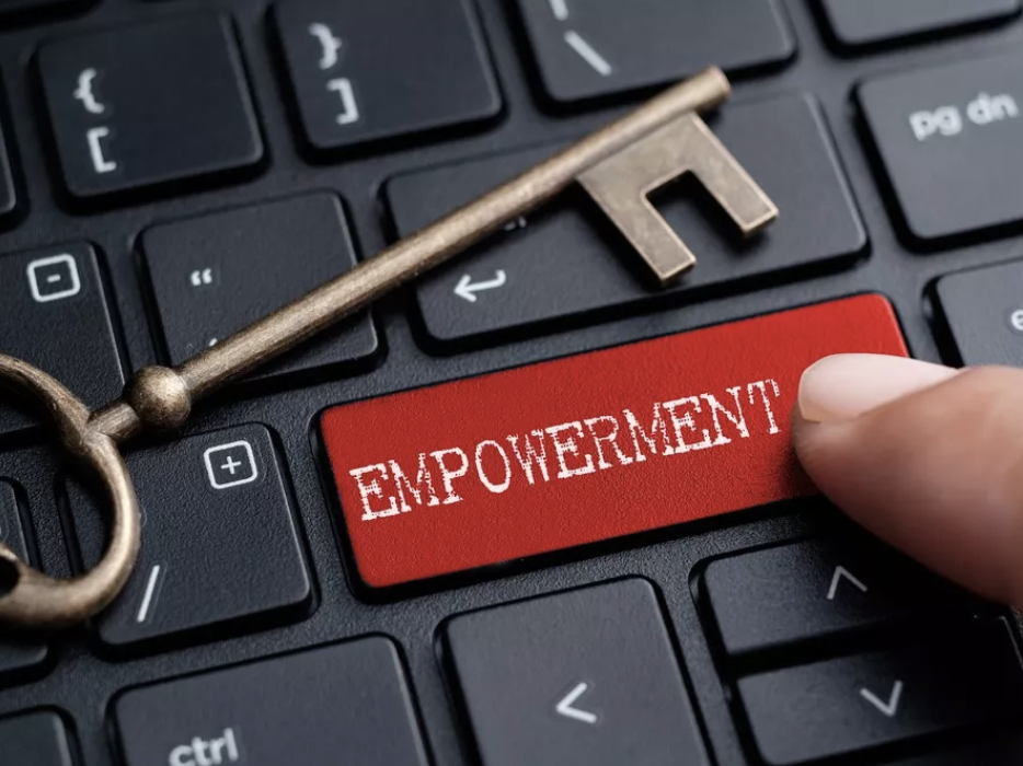 A computer keyboard with a house key sitting beside the word EMPOWERMENT 